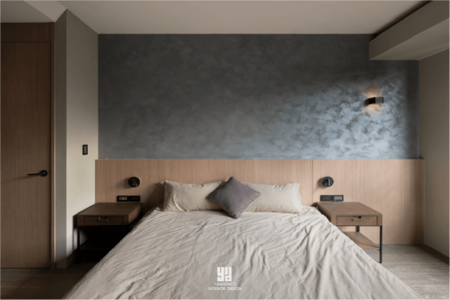 泰御天鑄主臥室設計：芽米設計以深灰色手工感藝術漆作為床頭主牆，結合原木色澤床頭板與質感壁燈，打造沉靜且具層次感的睡眠空間。