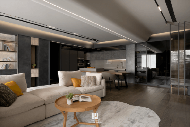 泰御天鑄室內實景：開放式客廳與廚房規劃，透過深灰色系建材與線性光影串聯，展現 Shade 案名中內斂且具深度的現代極簡空間。
